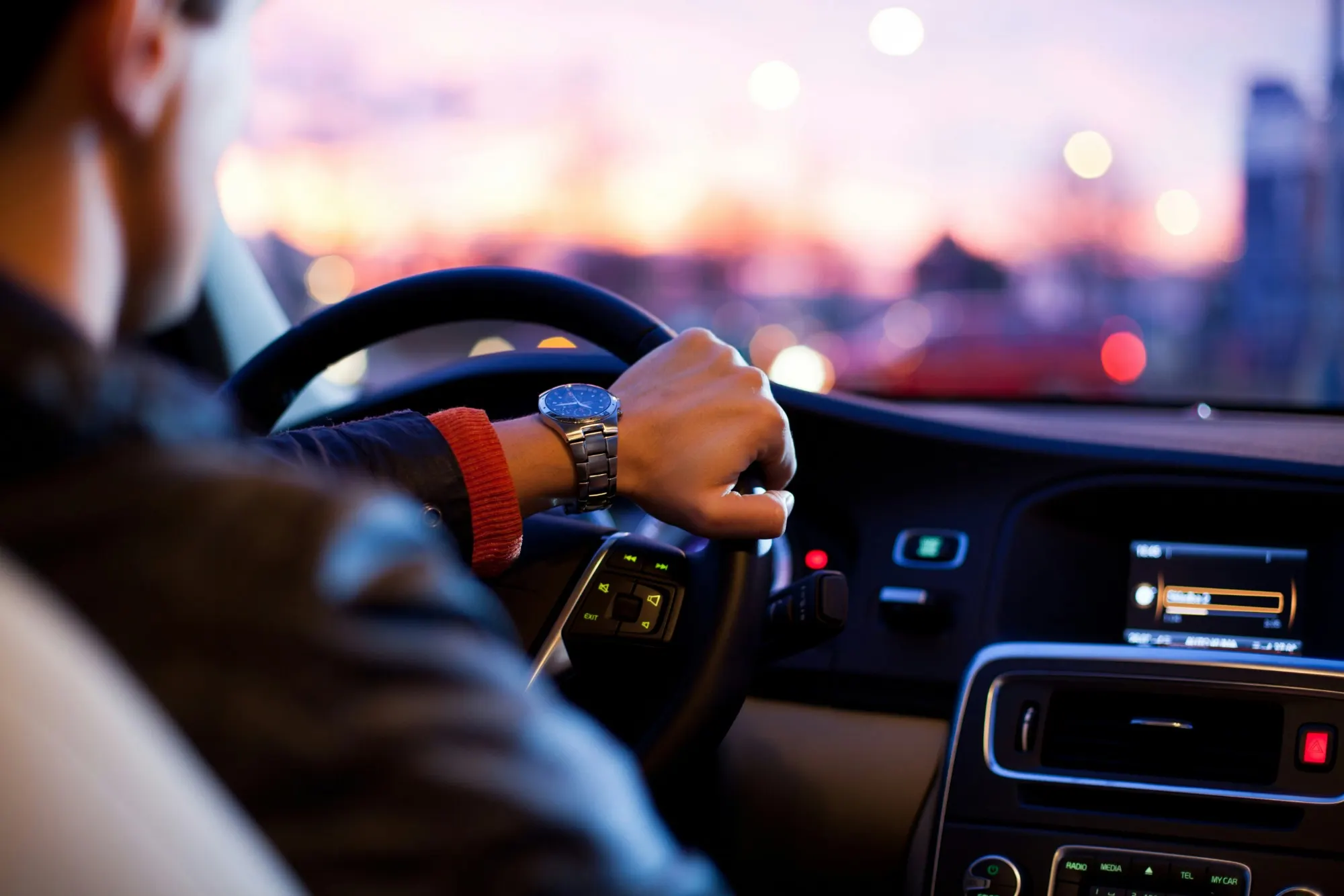 A chauffeur driving through a city at dusk